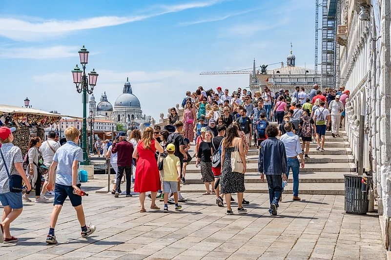 Crowds of tourists strolling on the cobblestone alley near Grand Canal in Venice